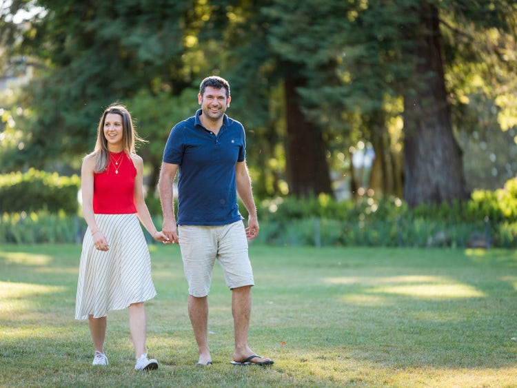 A happy man and woman walking in a park, backlit by the sun